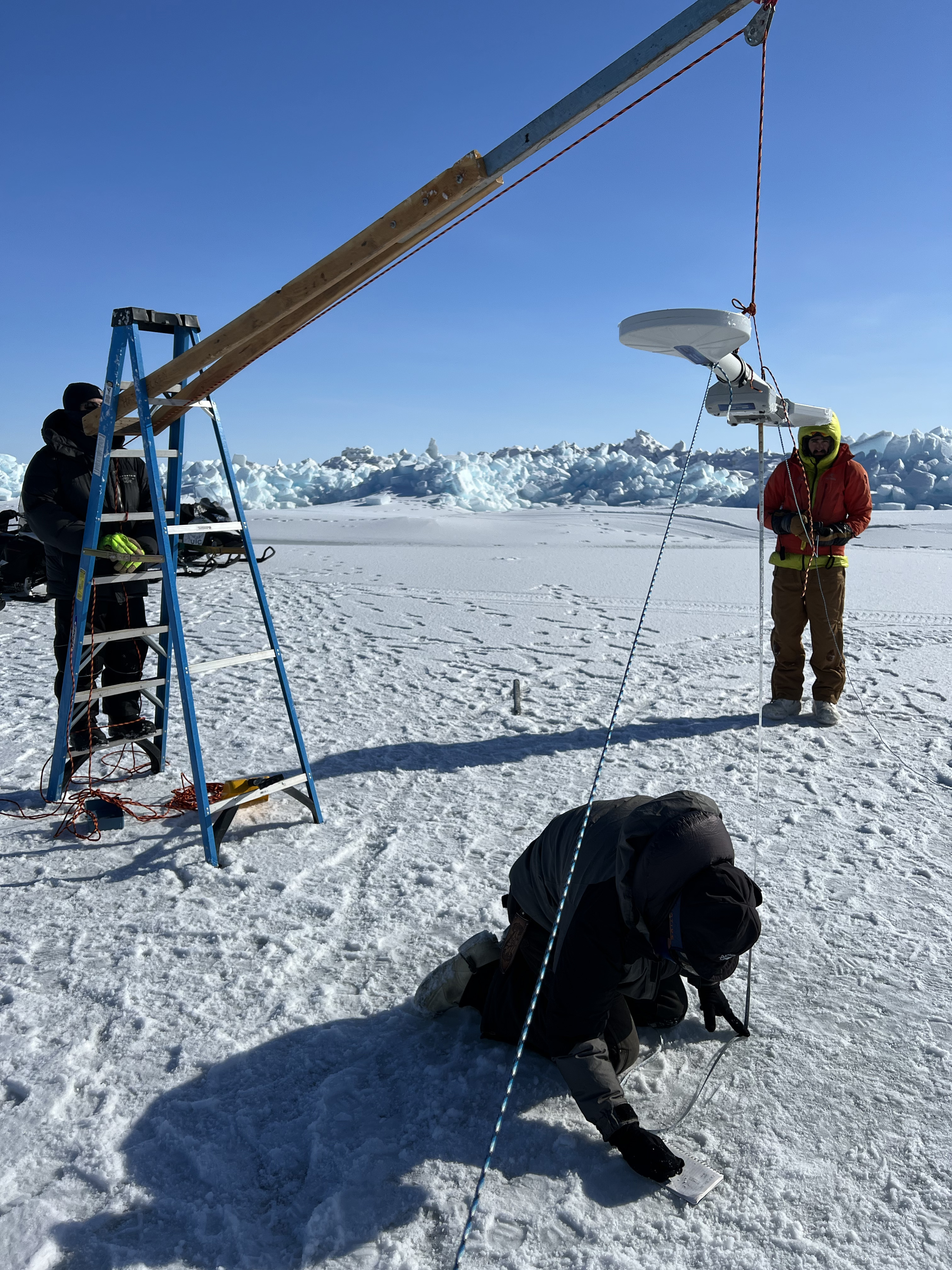 ELOKA researcher works with local community members to measure sea ice quality