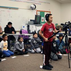 child holds boom while filming in classroom