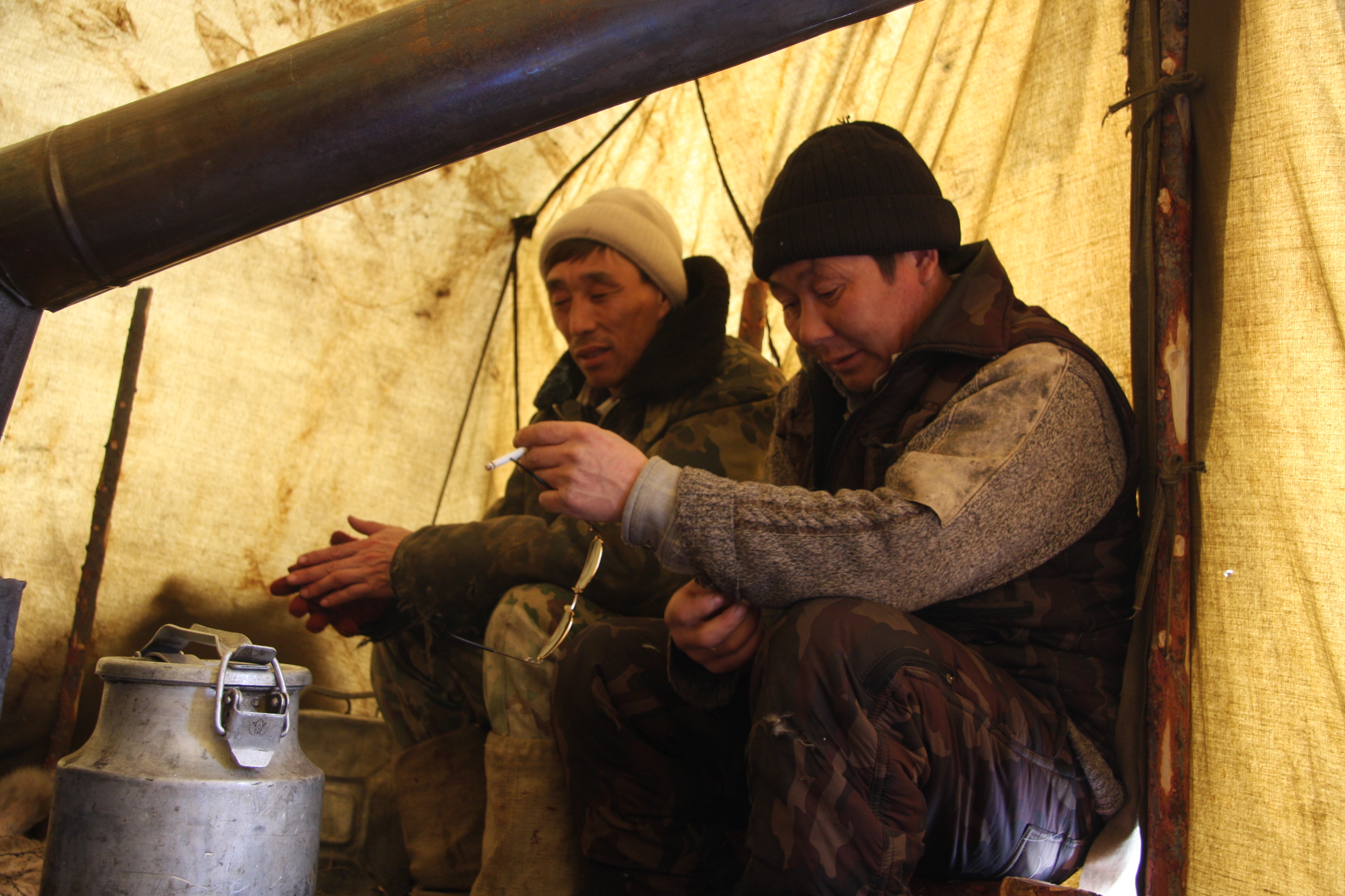 On the left, Vladimir Kolesov, a reindeer herder and oral historian, rests inside the Reindeer Brigade 4 camp in Siberia, Russia