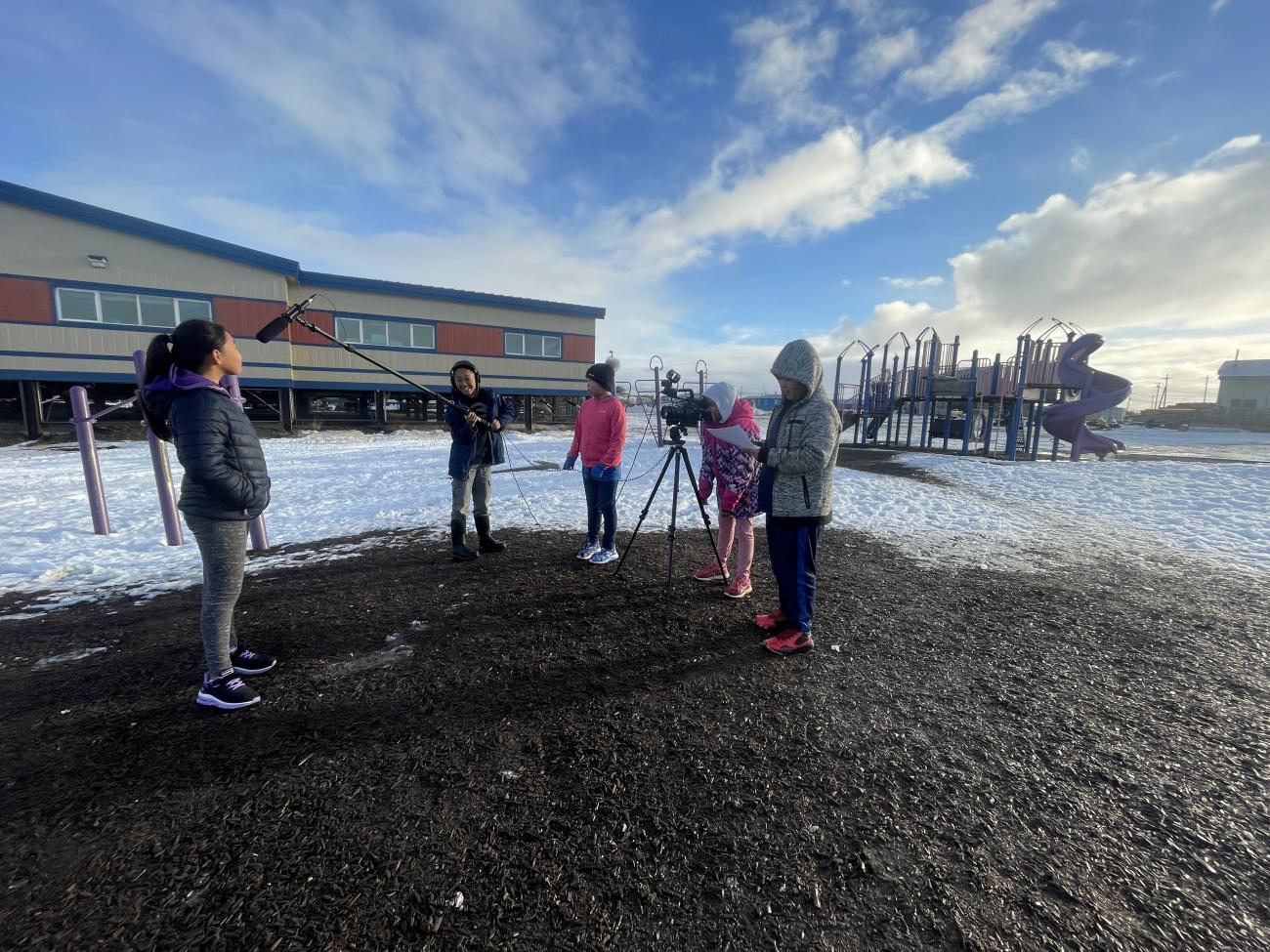 Students film a peer in front of the Chevak school and playground. — Credit: Seth Bader, See Stories