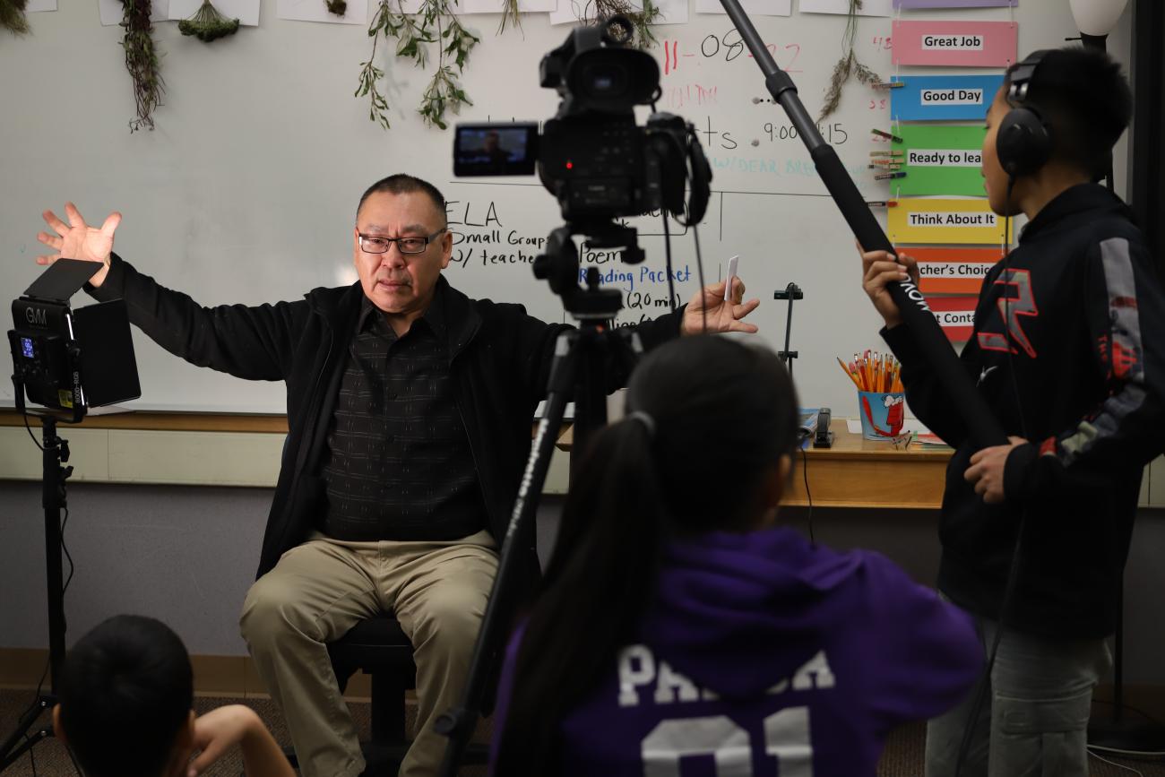 Elder Earl Atchak speaks to the classroom while being filmed by students